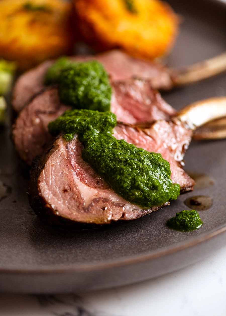 Close up of slices of rack of lamb with Salsa Verde sauce