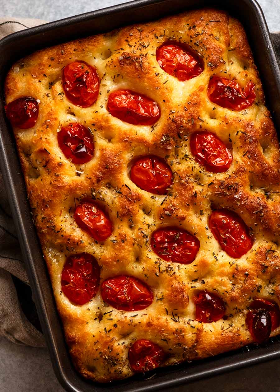 Overhead photo of tomato focaccia in a pan, fresh out of the oven