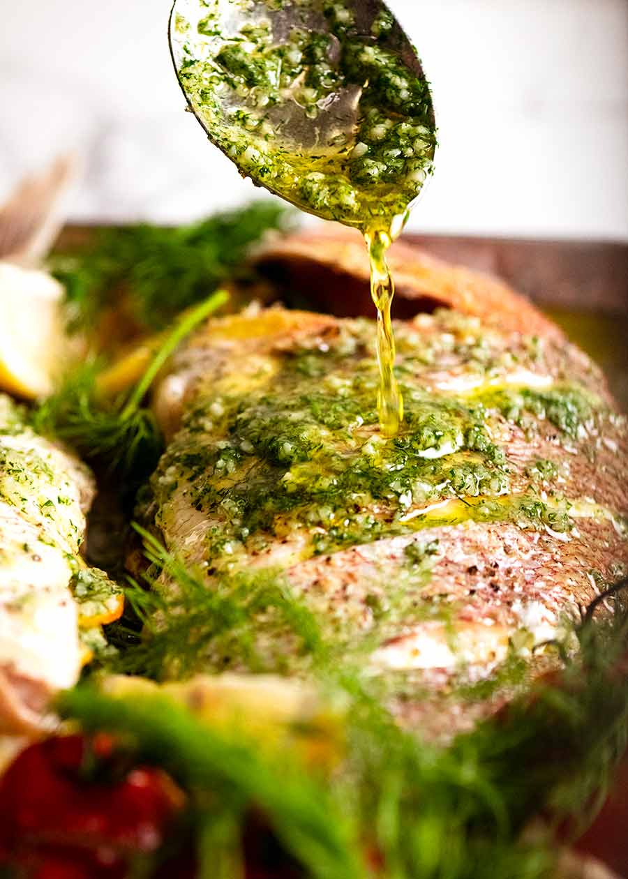 Drizzling garlic dill butter of whole baked snapper