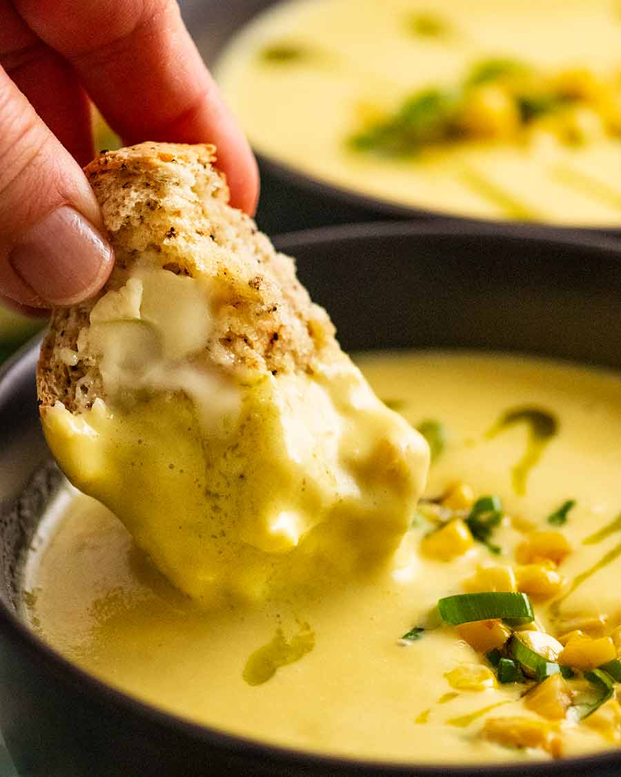 Dipping bread into a bowl of Cold Corn Soup for summer