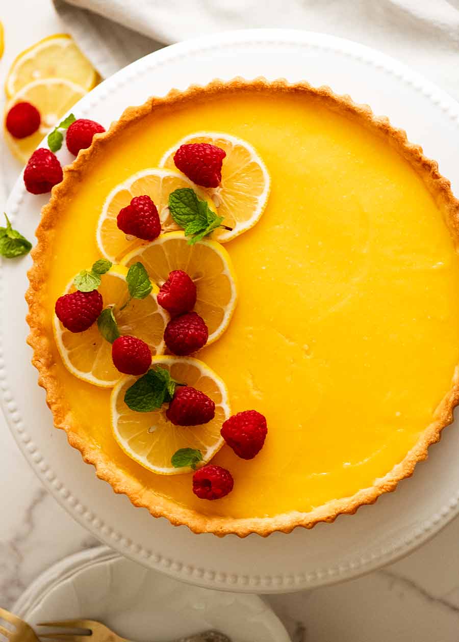 Overhead photo of French Lemon Tart decorated with raspberries and creme fraiche
