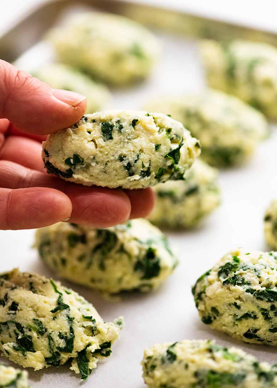 Hand holding a Malfatti - Italian Spinach Ricotta Dumplings, ready to be cooked
