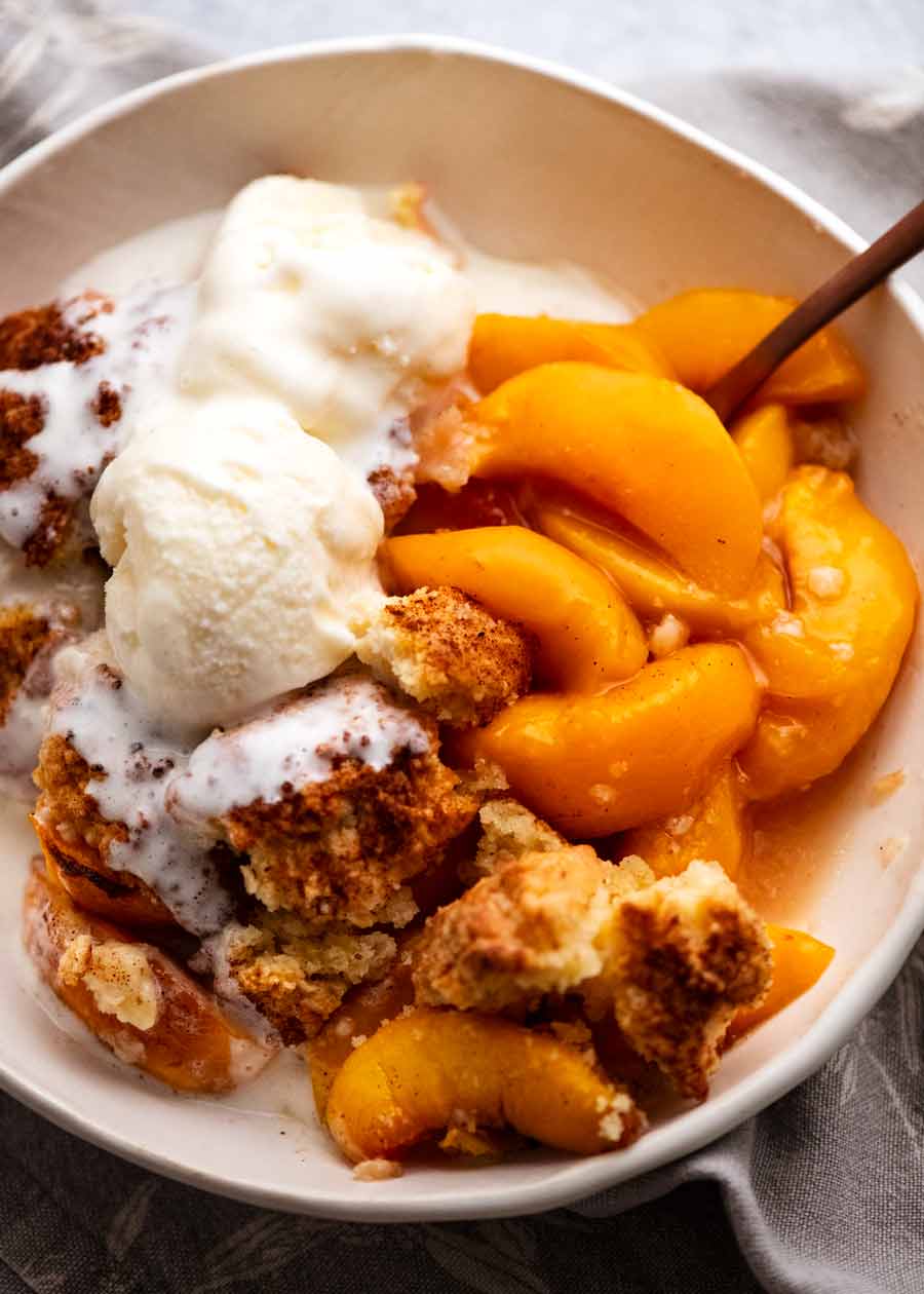 Peach Cobbler in a bowl with vanilla ice cream
