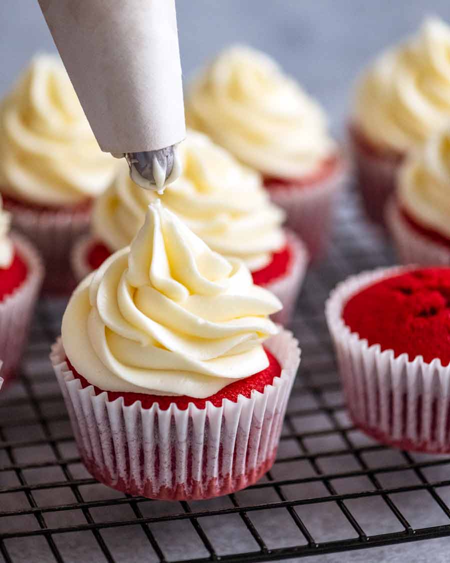 Piping cream cheese frosting onto Red Velvet Cupcakes