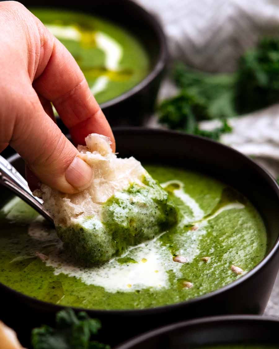 Dunking bread into Immunity Boosting Green Goddess Soup