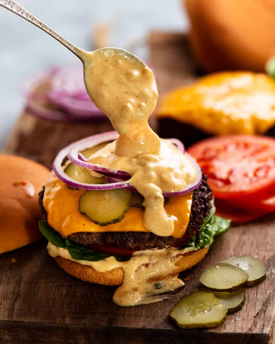 Spooning Special burger sauce onto a cheeseburger