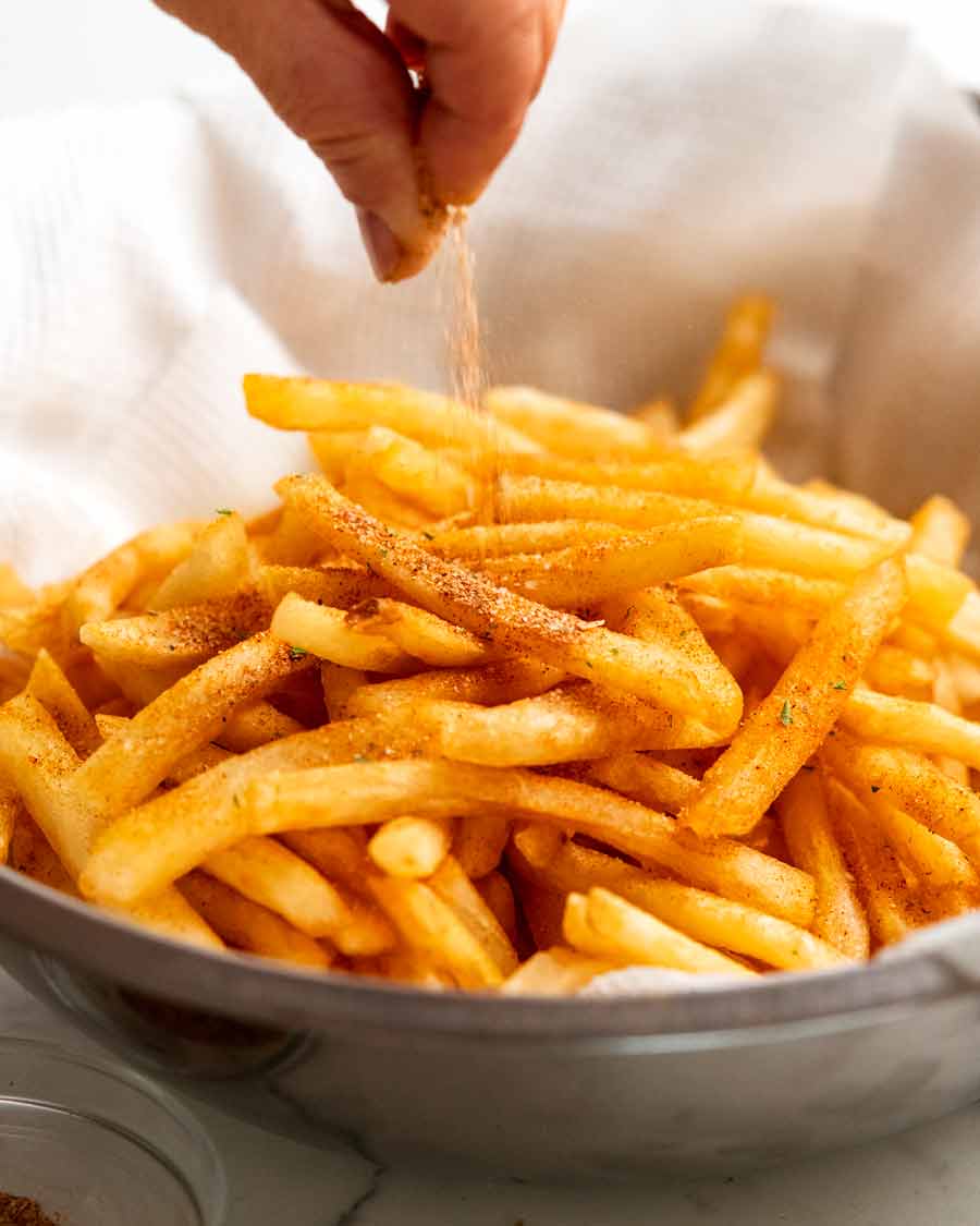 Sprinkling French fries seasoning on French fries