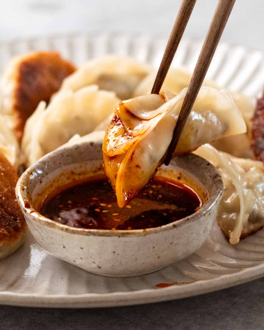 Dipping Vegetable Dumplings (Potstickers) in chilli soy dipping sauce