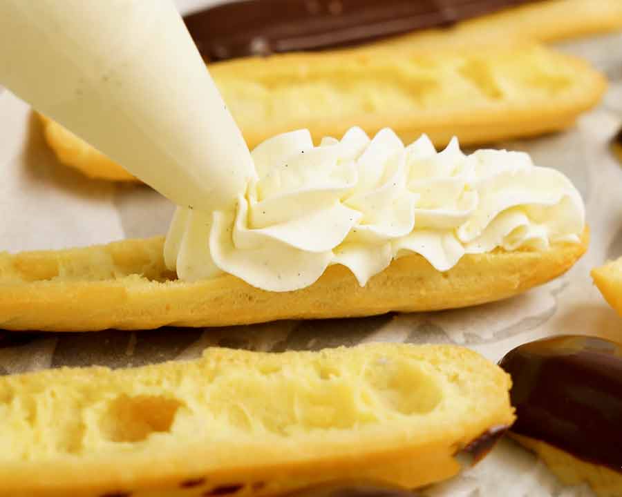 Piping whipped cream into an eclair