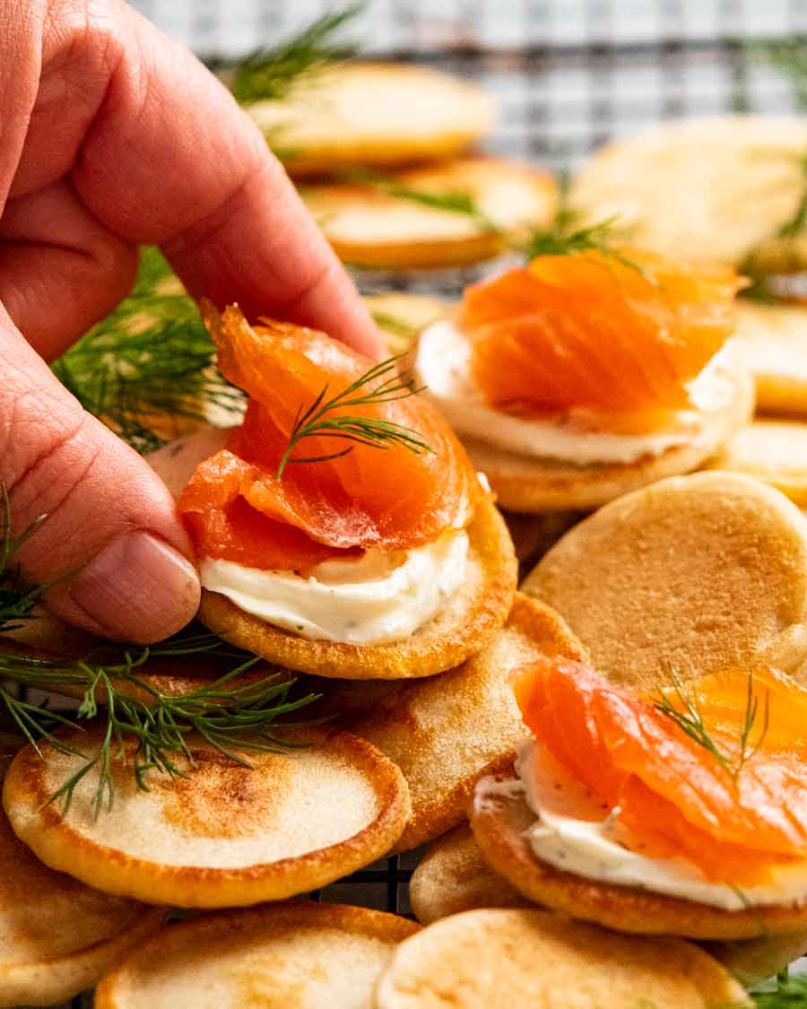Hand picking up Blini with smoked salmon