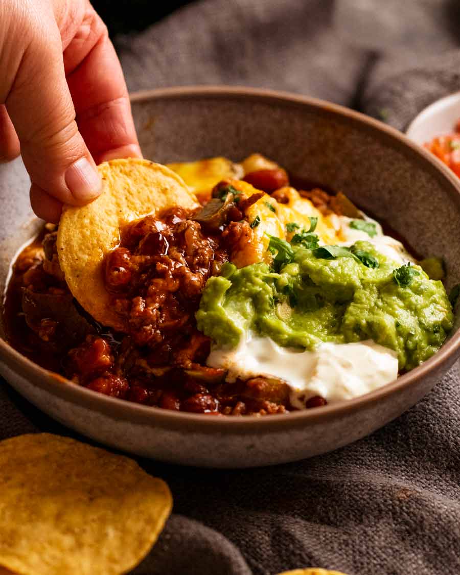 Scooping up Cheesy Mexican beef and bean casserole with corn chips