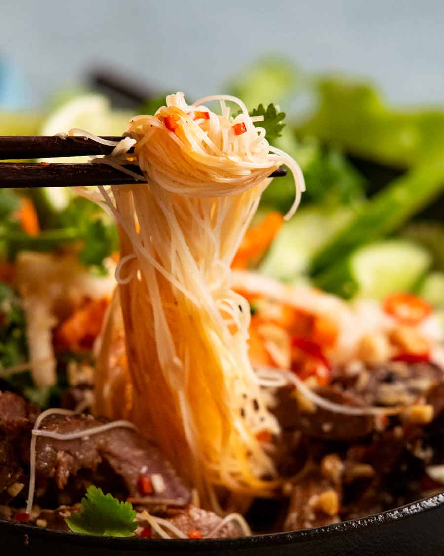 Chopsticks picking up noodles from Vietnamese noodles with lemongrass pork (Bún thịt nướng) noodle bowl