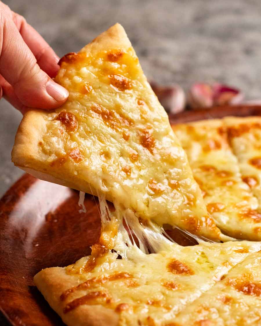 Recogiendo una rebanada de pizza de queso con ajo