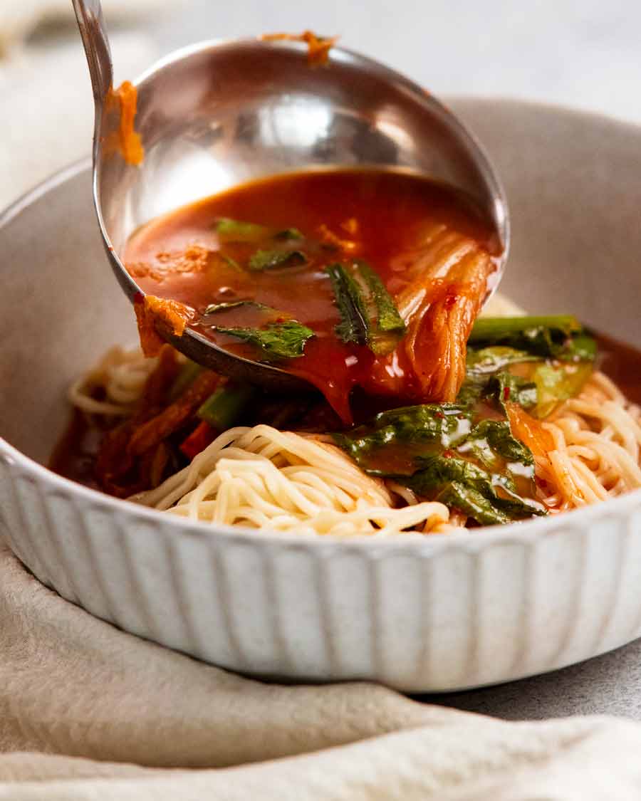 Ladling broth over Spicy Korean noodle soup